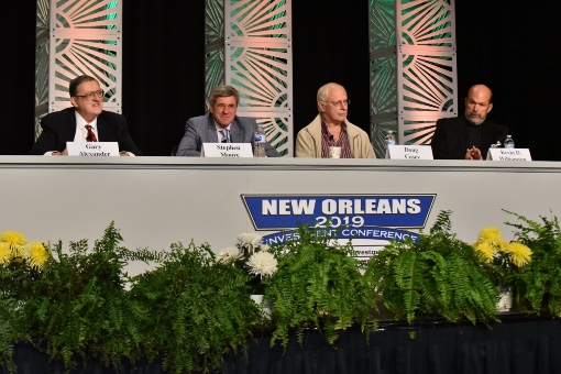 Conference speakers on stage at panel table
